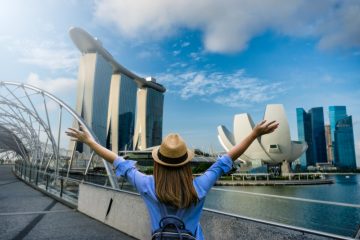 Young woman traveler with backpack and hat traveling into singapore city downtown