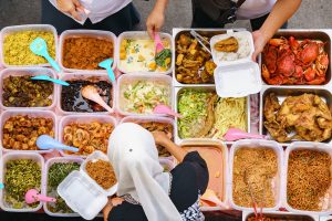 Overhead shot of people buying food over variety of delicious Malaysian home cooked dishes